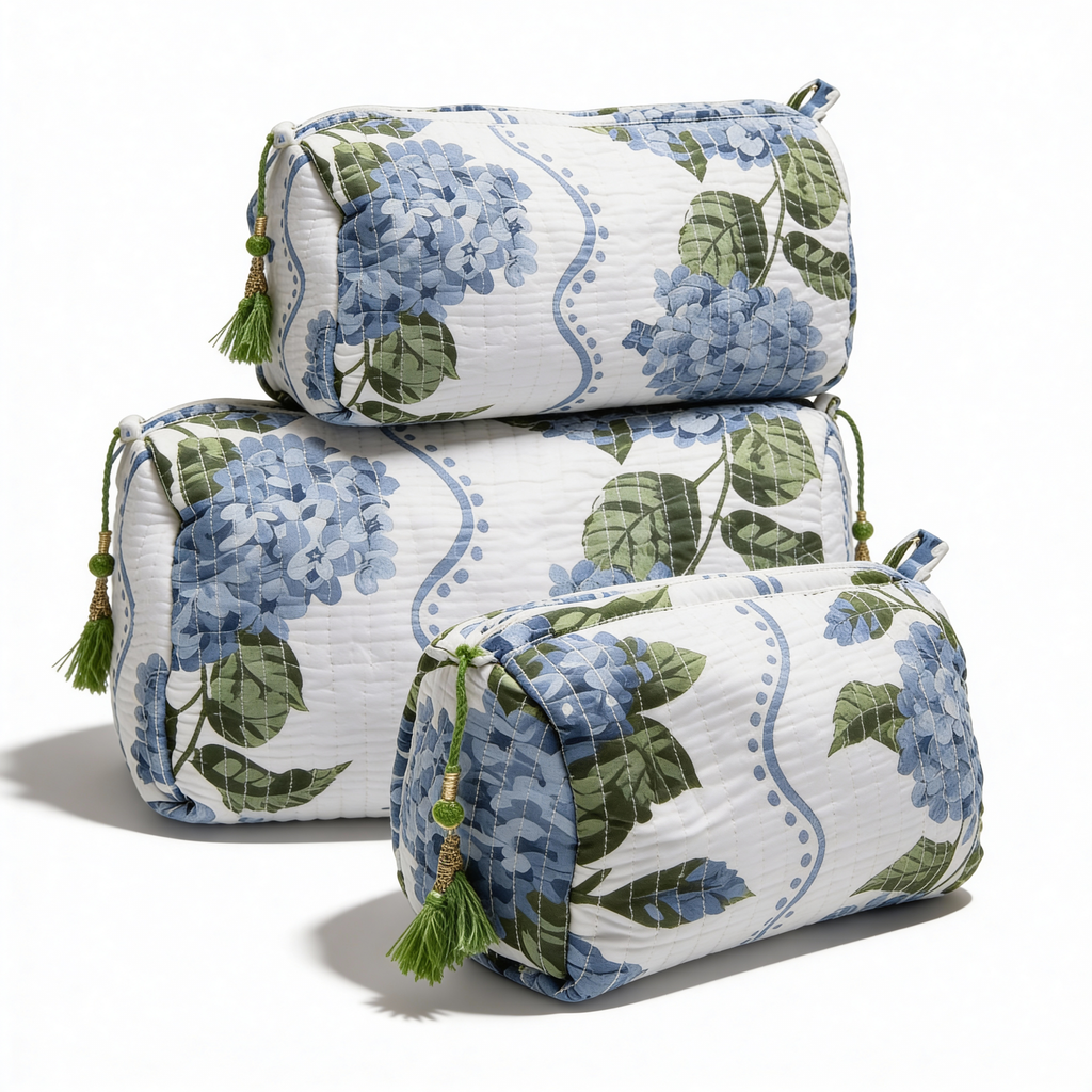 Trío de bolsas de aseo acolchadas en tres tamaños, apiladas para mostrar el diseño floral de hortensias y los acabados de lujo.