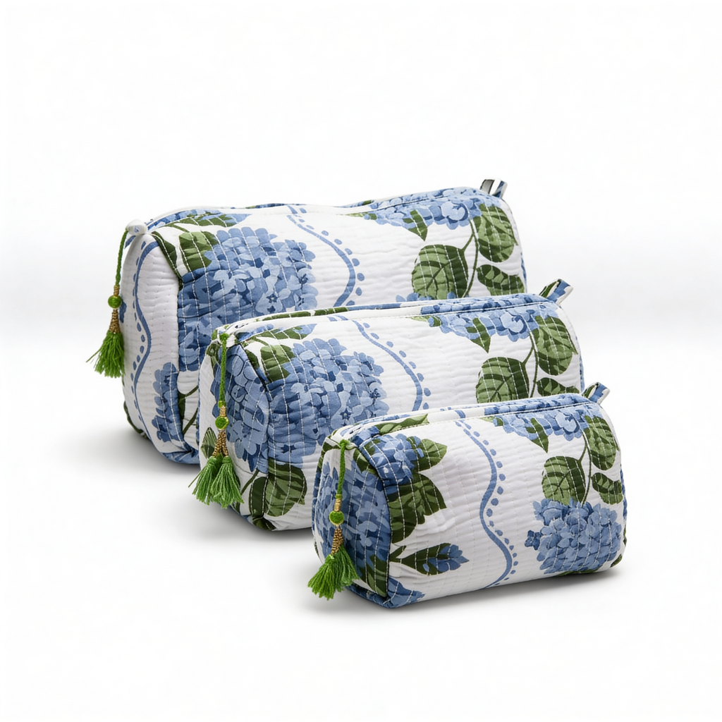 Set de tres neceseres de diferentes tamaños con estampado de hortensias azules, acolchados y con detalle de borla verde en la cremallera.