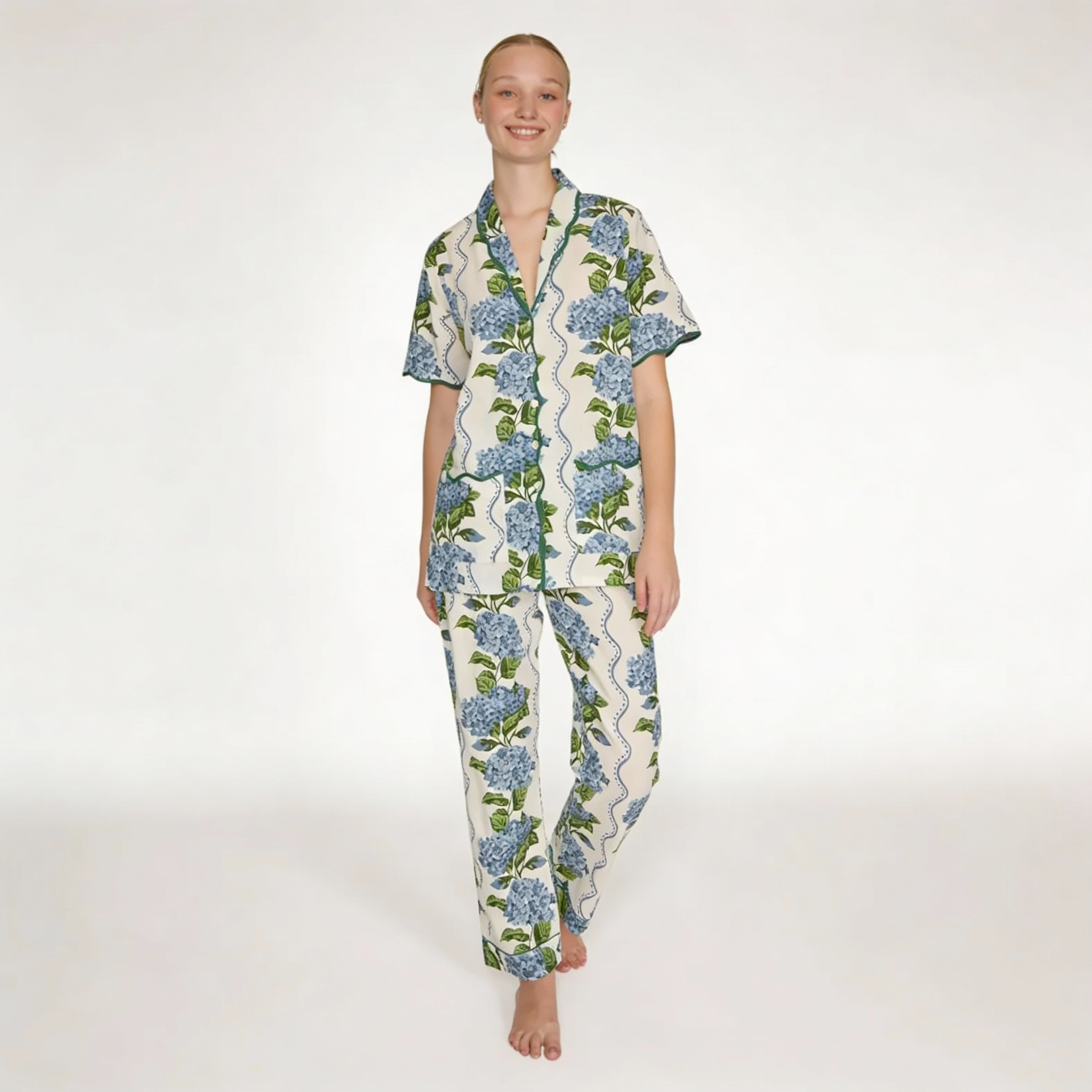 Modelo de pie luciendo un pijama largo de dos piezas con estampado de hortensias azules, camisa de manga corta y pantalón recto sobre fondo blanco.
